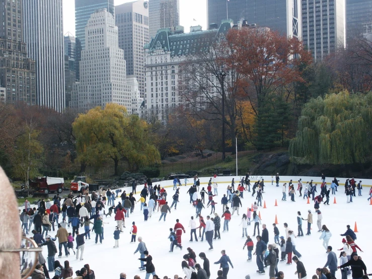 many people ice skating on the ice rink in central park