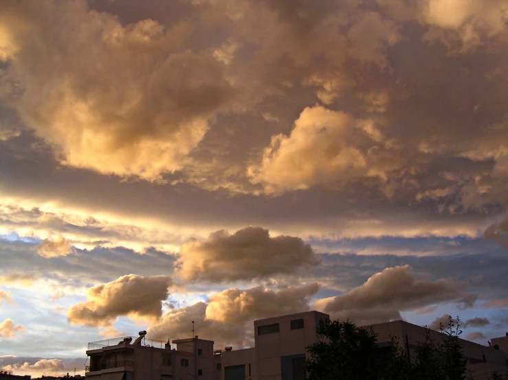 a number of buildings near one another with a sky filled with clouds