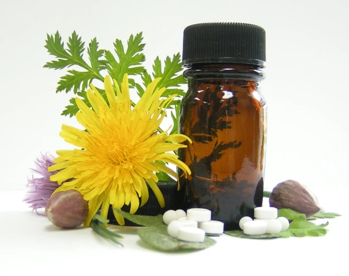 there is a bottle with two medicine bottles and a vase filled with flowers