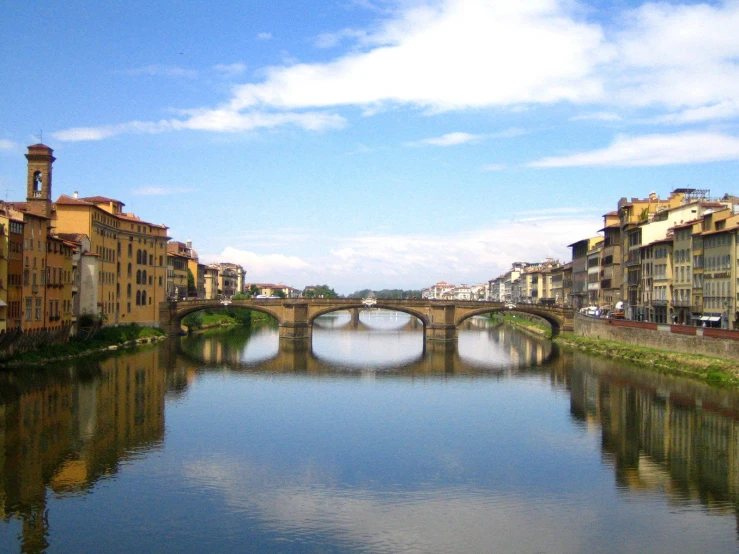 the bridge is above a river and a few buildings