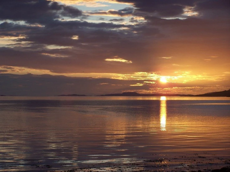 the sun is setting behind the clouds at sea