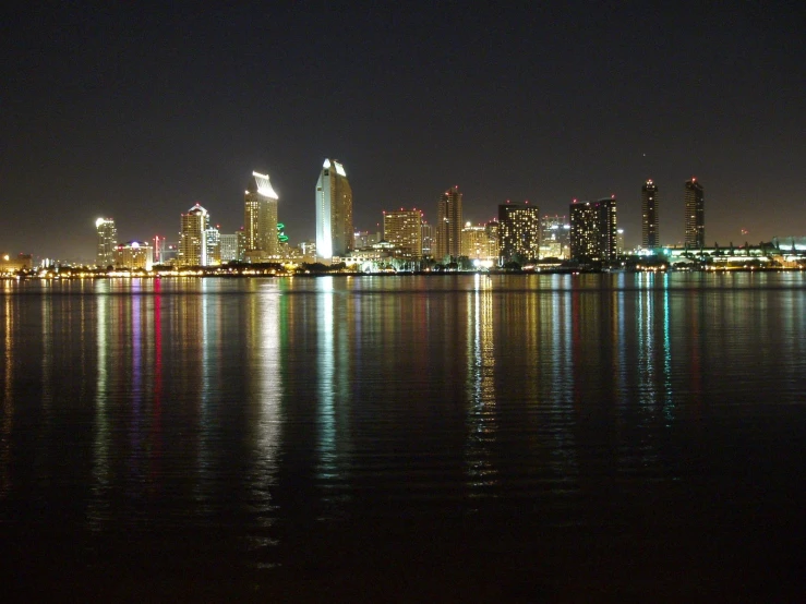 city lights reflect off of the water at night