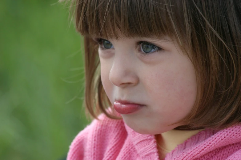 a small child with blue eyes wearing a pink sweater