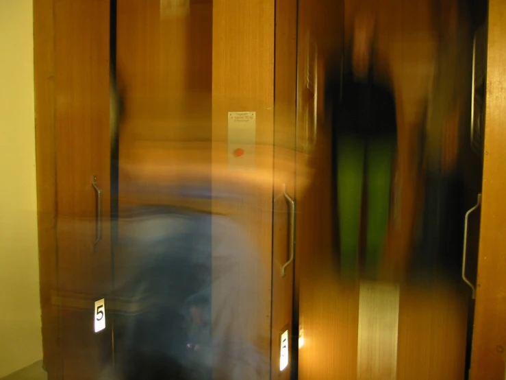 blurry pograph of wooden cupboards with people in it