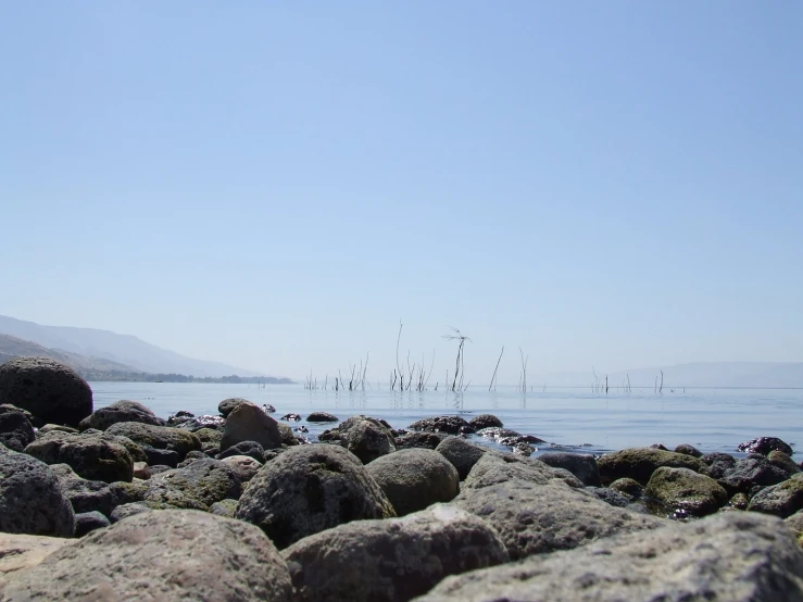 a rock beach and sea and boat on water