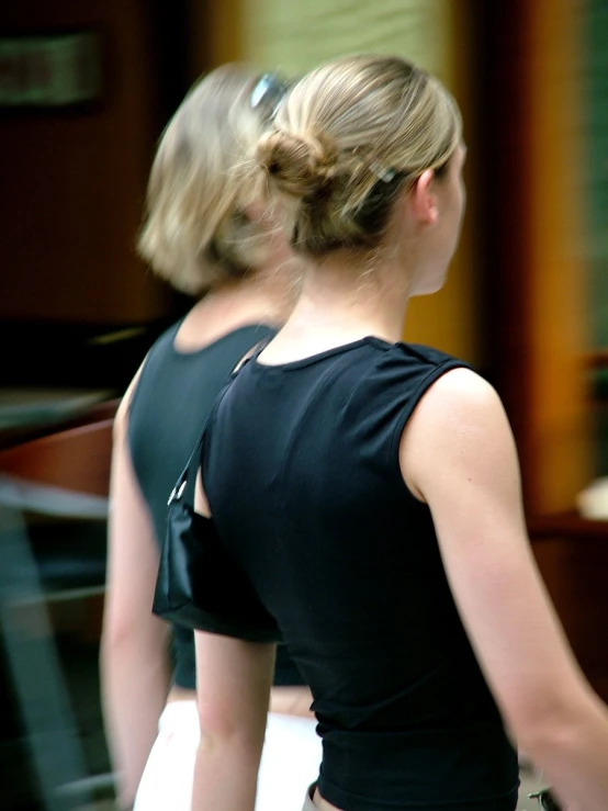 two woman in black dresses one in a backless position