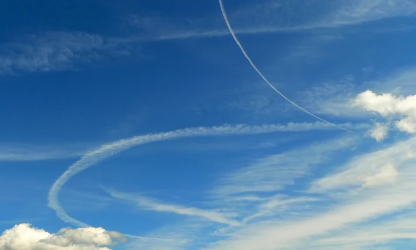 two planes flying in a blue sky with contrails in the middle