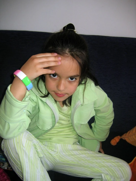 a little girl sitting on top of a black couch