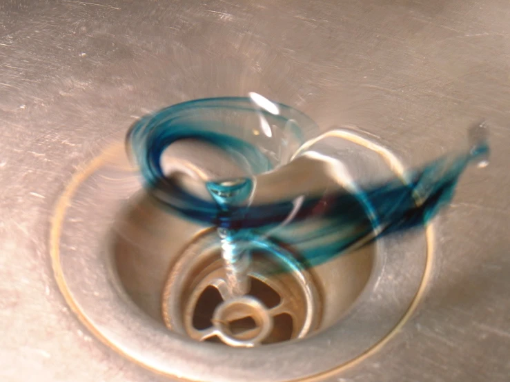 blue streamy liquid coming out of the water into the sink