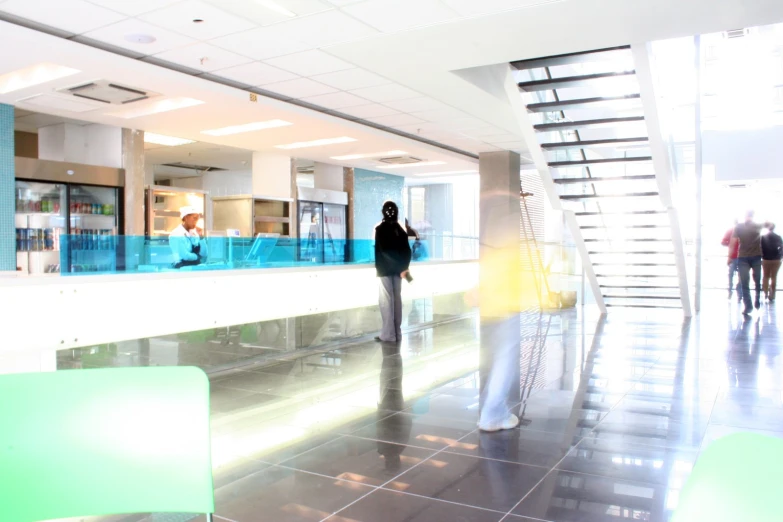 the lobby has stairs with some windows and people walking around