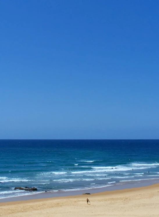 a beach with people walking in the water and the ocean