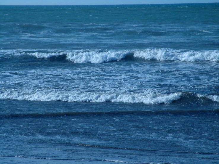 two ocean waves rolling up the side of an ocean shore