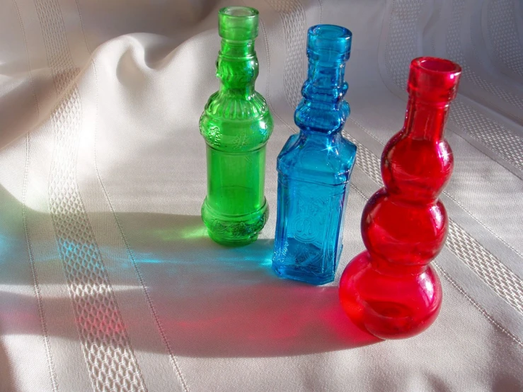 three vases that are made to look like colored bottles