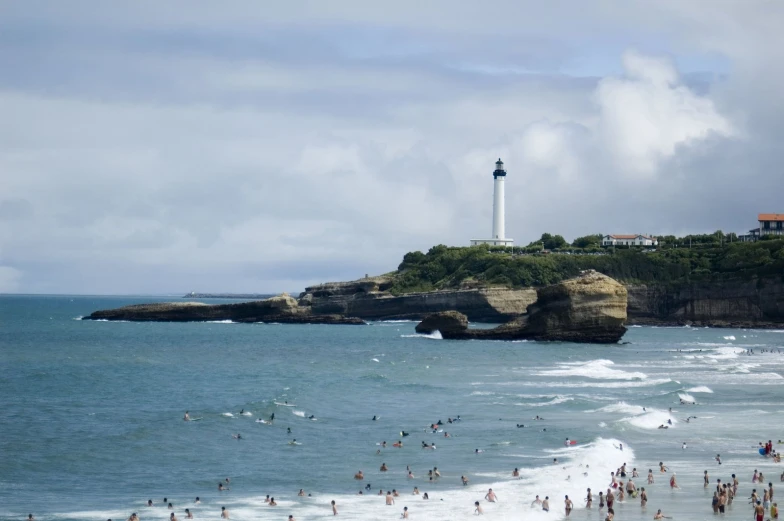 a beach filled with lots of people and a light house