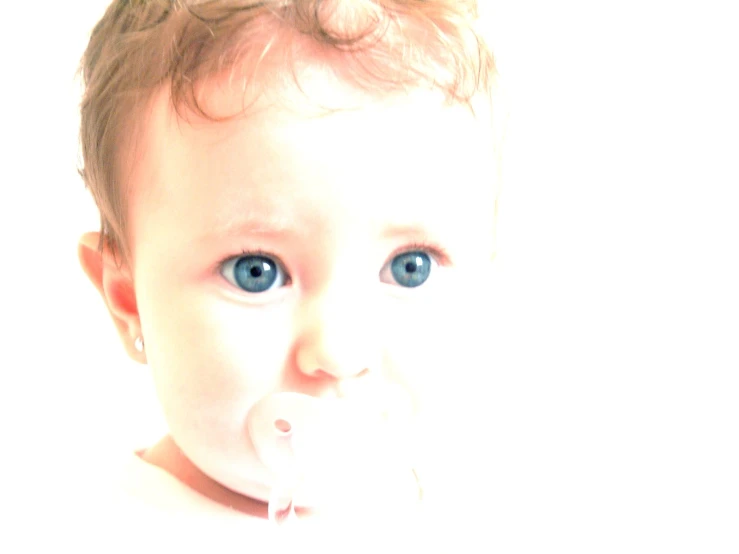 the face of a baby with a plastic pacifier