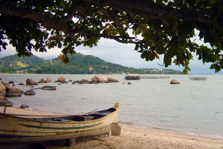 a beach area with a boat, shore, and other body of water