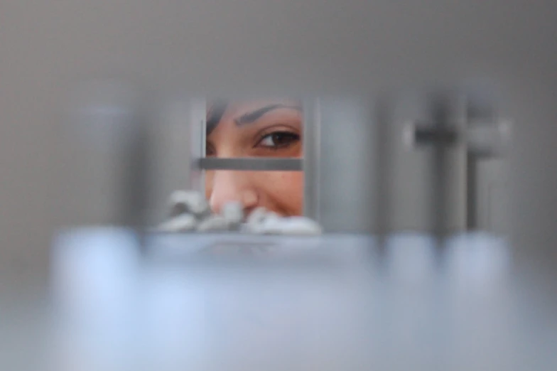 a woman looking through the bars of a prison cell