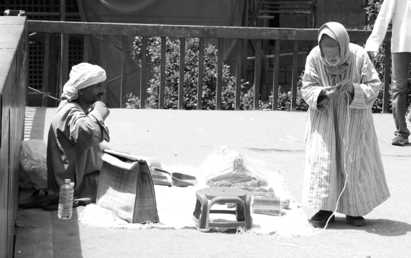 two women with long robes stand outside near a toy car