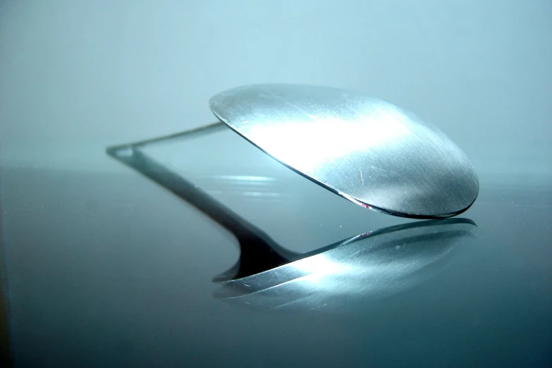 silver object placed on a white surface with reflection