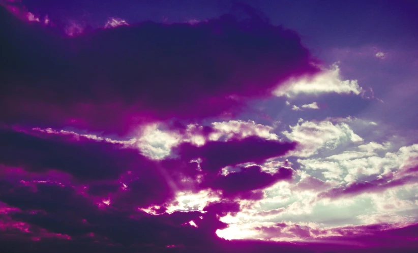 purple sky with several clouds and a plane