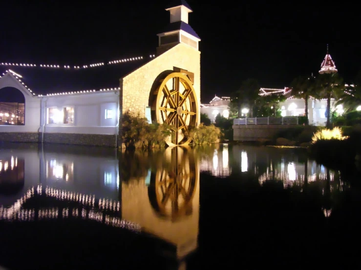 a church lit up at night with a pond in front