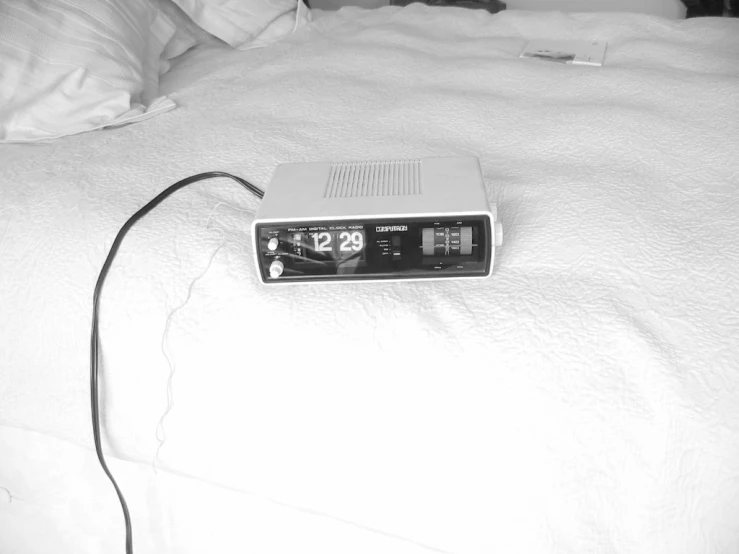 an alarm clock sits on top of a bed