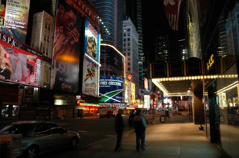 two people walking down a city street at night