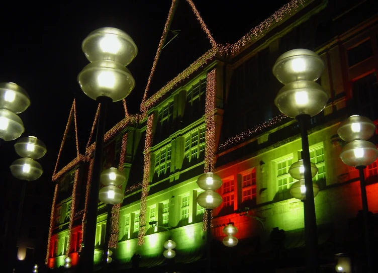 several lights lit up along a building and some trees