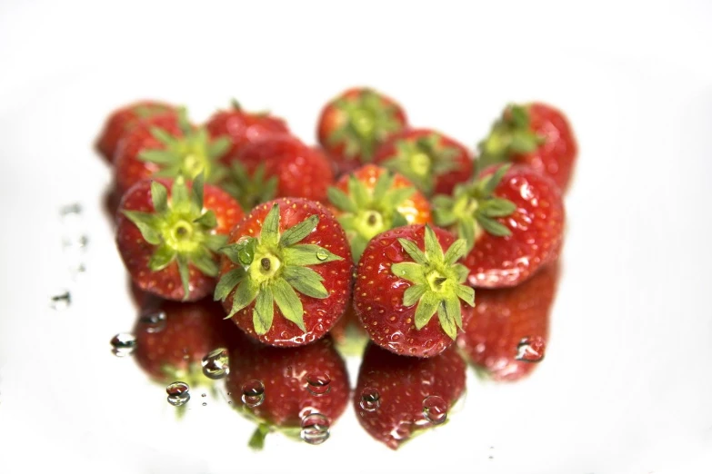 red berries with green tips sitting on white plate