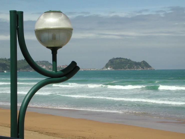 the lamp is hanging off of the pole on the beach