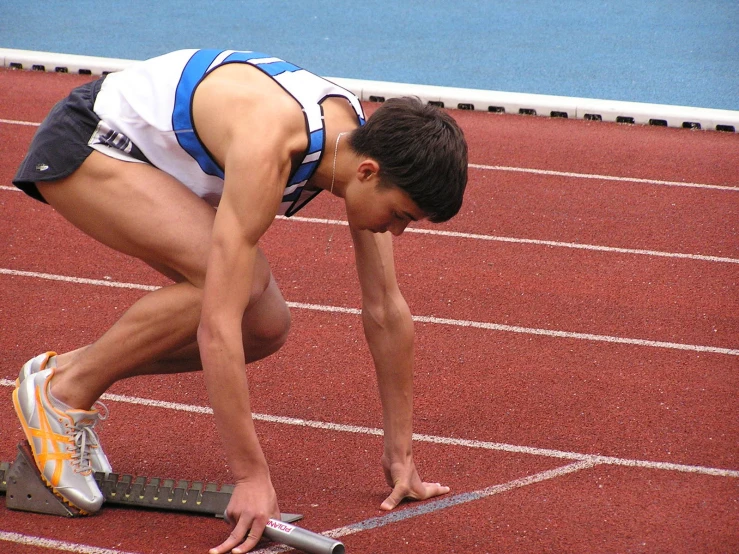 a man kneeling down and holding a skateboard on a track