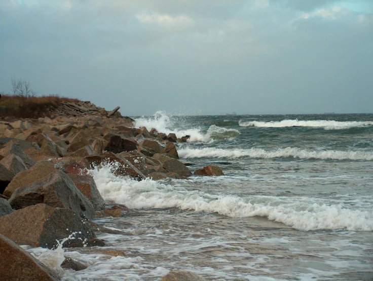 the water and rocks at the shoreline is foamy