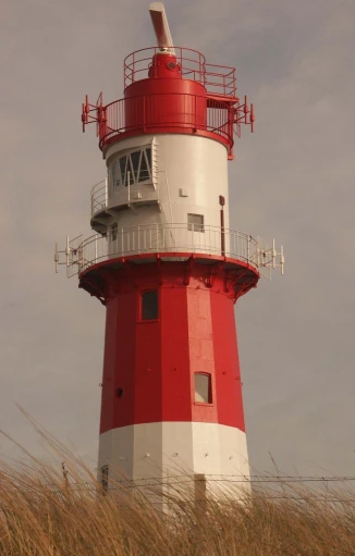 a red and white lighthouse near some tall grass