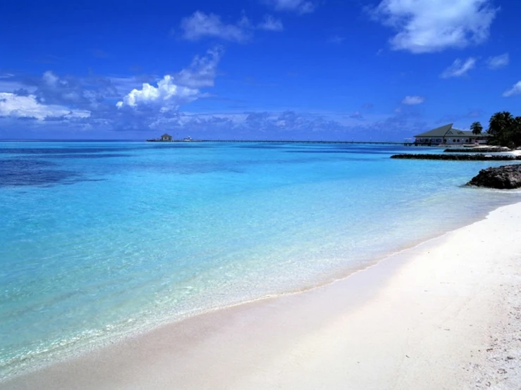 a beach with clear blue waters and an island in the distance