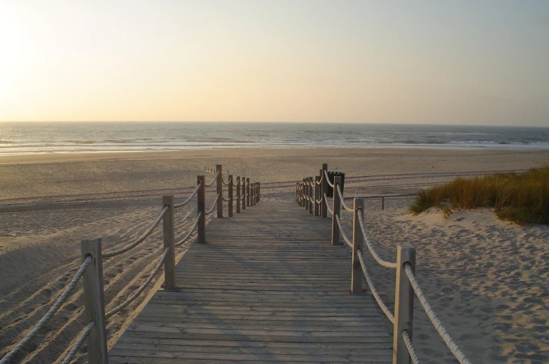 a long walkway along the beach towards a small beach