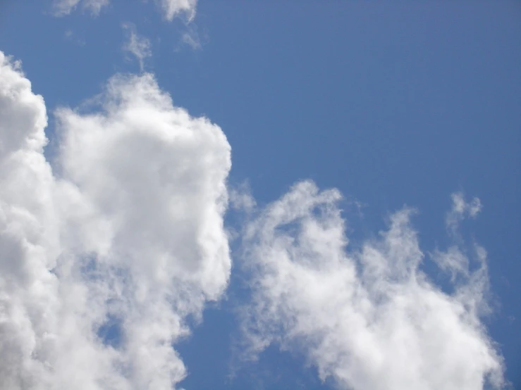 an airplane flying through the sky, clouds in the background