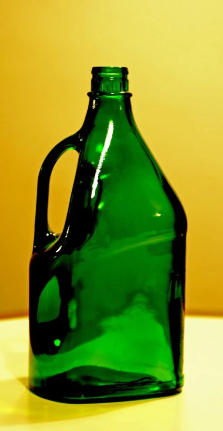 a green glass bottle sitting on top of a table