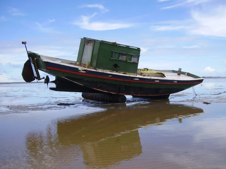 an old boat is on the edge of a muddy beach