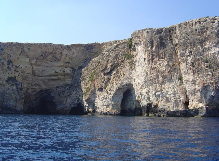 water next to rocks with cave on both sides