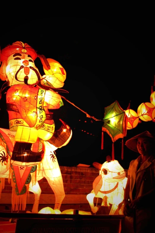 many colorful lanterns shine brightly at night with people around