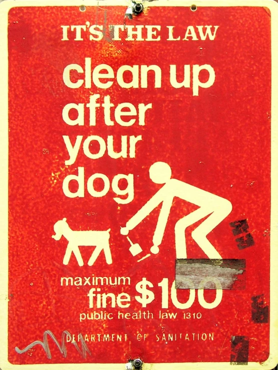 a red sign with white writing stating it's the law clean up after your dog