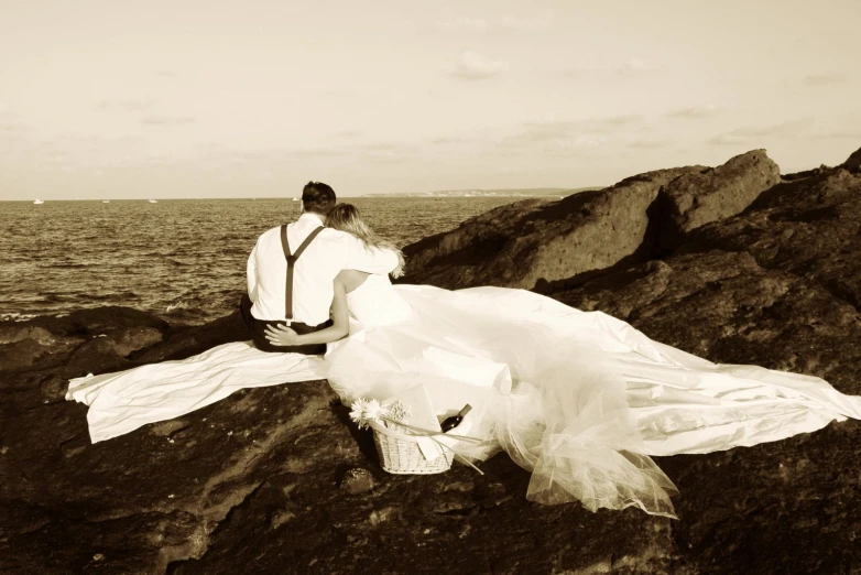 a man and a woman dressed up sit on some rocks