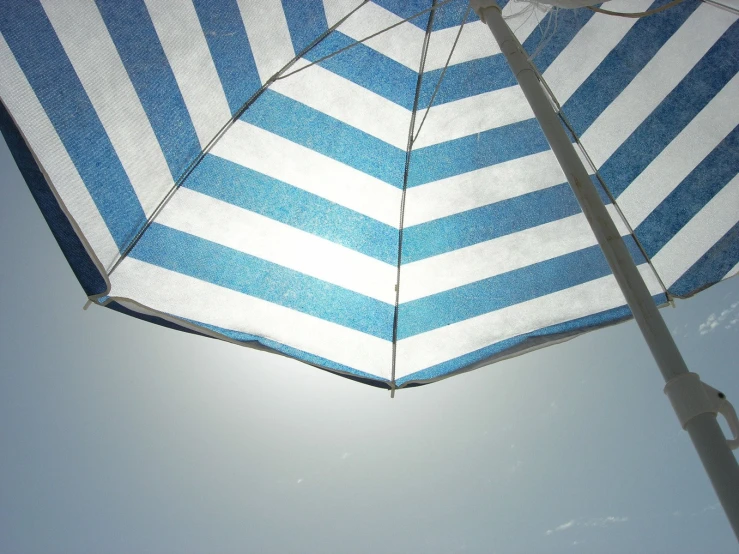 a blue and white umbrella sitting against the blue sky