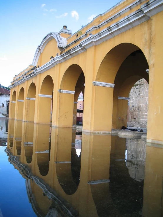 a reflection in water of arches on a street