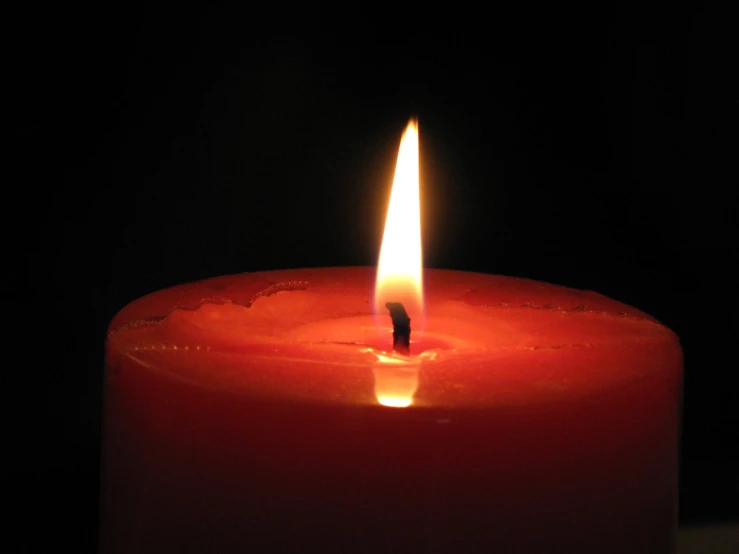 a lit candle is being shown in front of a dark background