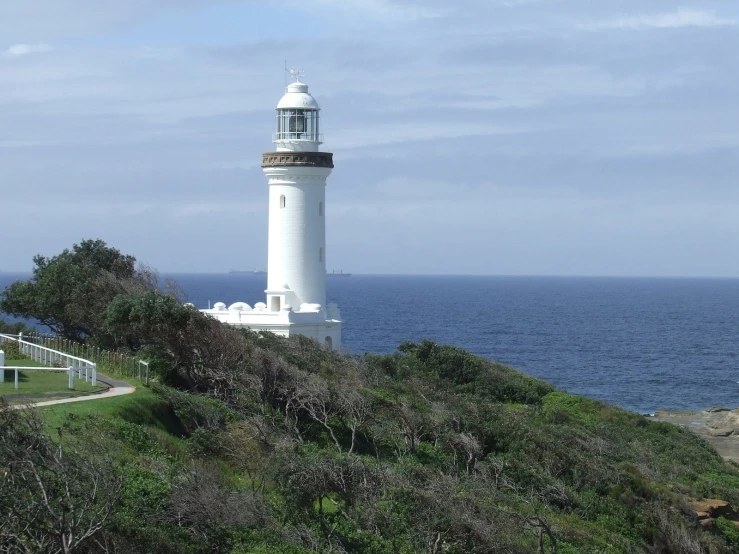 a lighthouse sitting on a grassy hill near the ocean