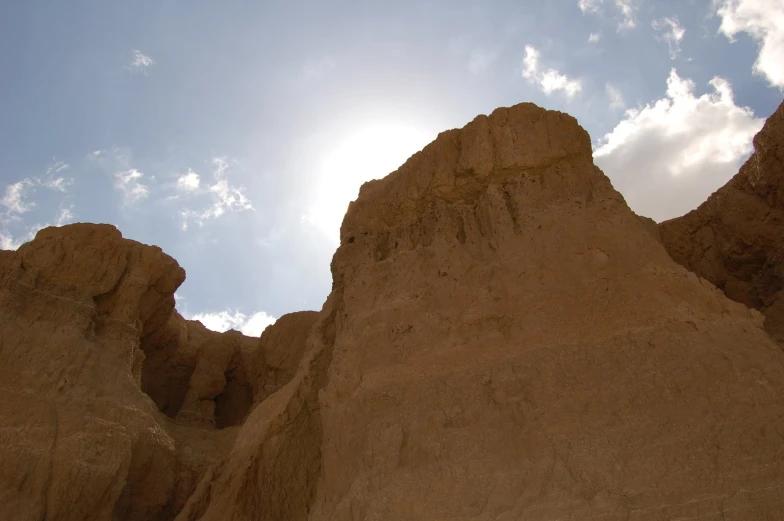 an upward view of some large mountains under the sun