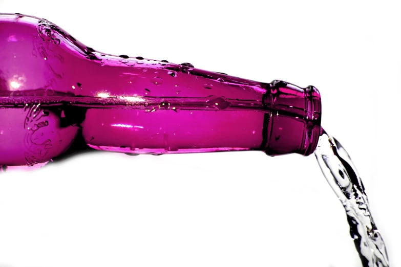 a large purple wine bottle being filled with water