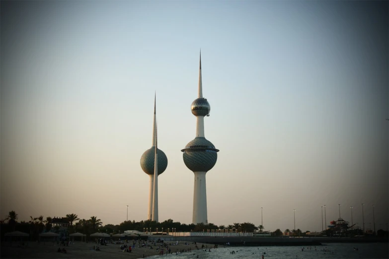 two tall buildings in the background with people on the sand