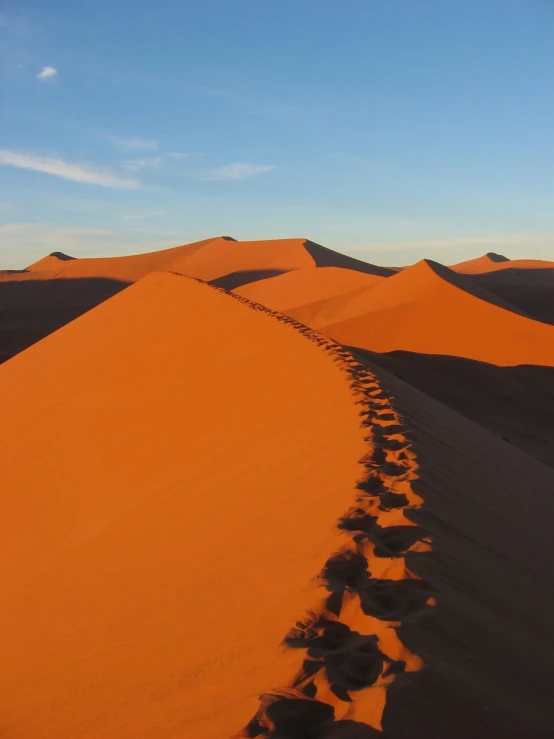 a small trail of footprints across sand dunes